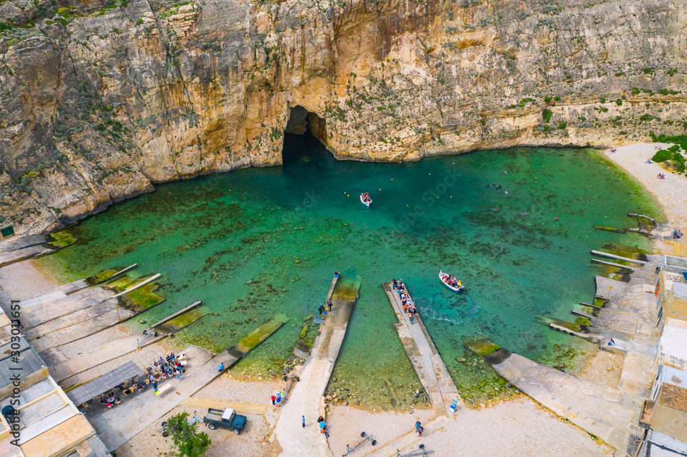 The Inland Sea and two tourist boat. Dwejra is a lagoon of seawater on the island of Gozo. Aerial view of Sea Tunnel near Azure window. Mediterranean sea. Malta country