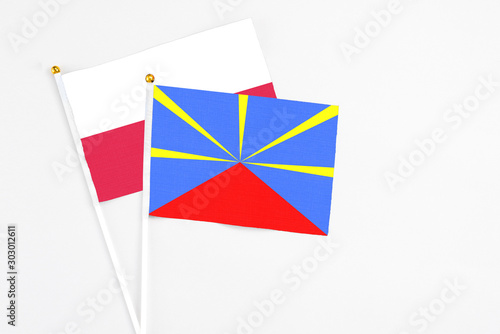 Reunion and Poland stick flags on white background. High quality fabric, miniature national flag. Peaceful global concept.White floor for copy space.