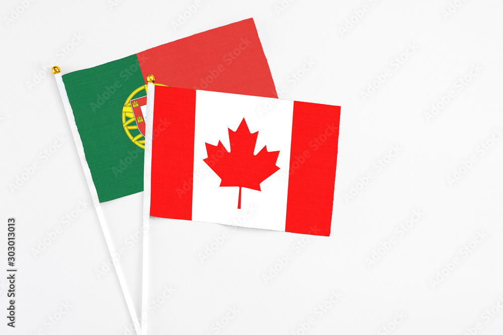 Canada and Portugal stick flags on white background. High quality fabric, miniature national flag. Peaceful global concept.White floor for copy space. Canada and Portugal stick flags on white background. High quality fabric, miniature national flag. Peaceful global concept.White floor for copy space.
