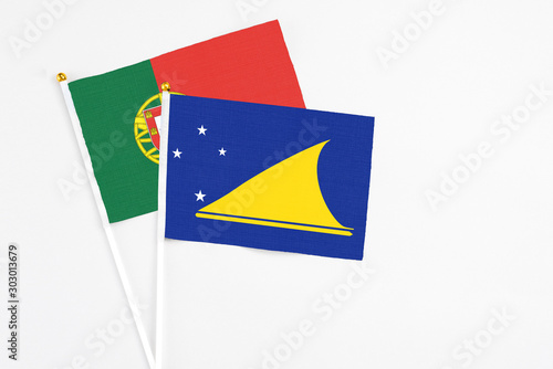 Tokelau and Portugal stick flags on white background. High quality fabric, miniature national flag. Peaceful global concept.White floor for copy space.