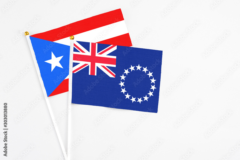 Fototapeta premium Cook Islands and Puerto Rico stick flags on white background. High quality fabric, miniature national flag. Peaceful global concept.White floor for copy space.