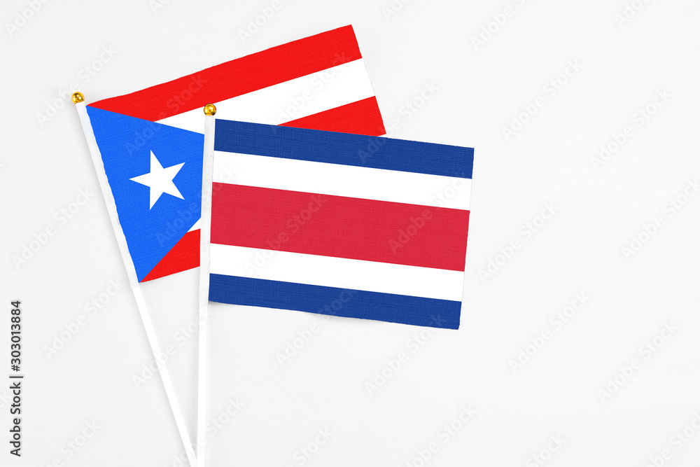 Costa Rica and Puerto Rico stick flags on white background. High quality fabric, miniature national flag. Peaceful global concept.White floor for copy space. Costa Rica and Puerto Rico stick flags on white background. High quality fabric, miniature national flag. Peaceful global concept.White floor for copy space.