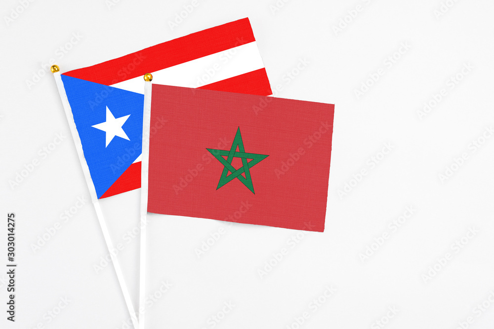 Morocco and Puerto Rico stick flags on white background. High quality fabric, miniature national flag. Peaceful global concept.White floor for copy space.
