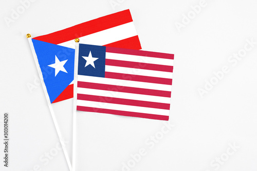 Liberia and Puerto Rico stick flags on white background. High quality fabric  miniature national flag. Peaceful global concept.White floor for copy space.