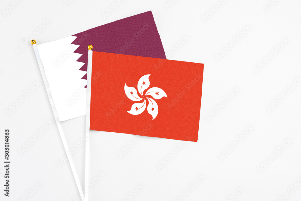 Hong Kong and Qatar stick flags on white background. High quality fabric, miniature national flag. Peaceful global concept.White floor for copy space.