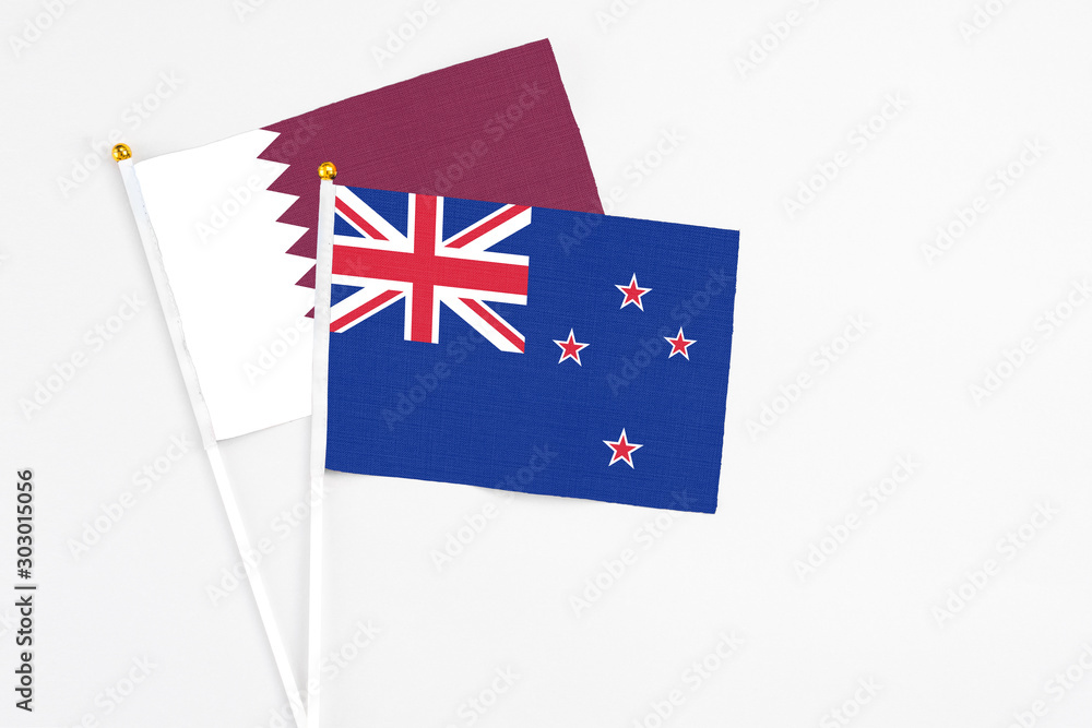 Fototapeta premium New Zealand and Qatar stick flags on white background. High quality fabric, miniature national flag. Peaceful global concept.White floor for copy space.