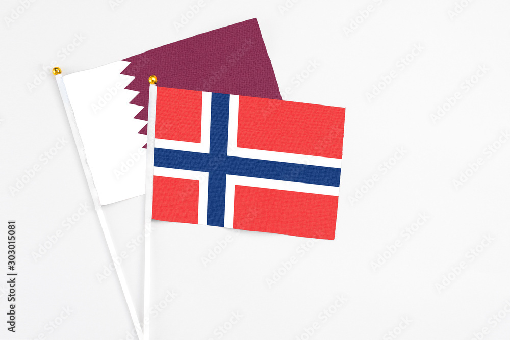 Norway and Qatar stick flags on white background. High quality fabric, miniature national flag. Peaceful global concept.White floor for copy space.