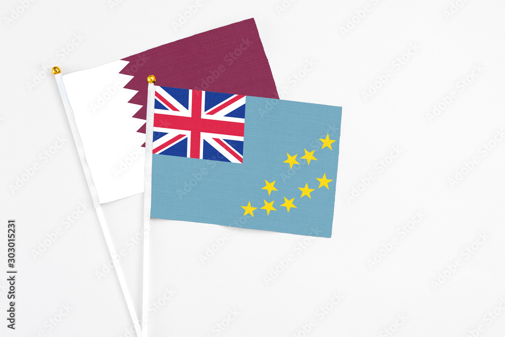 Fototapeta premium Tuvalu and Qatar stick flags on white background. High quality fabric, miniature national flag. Peaceful global concept.White floor for copy space.