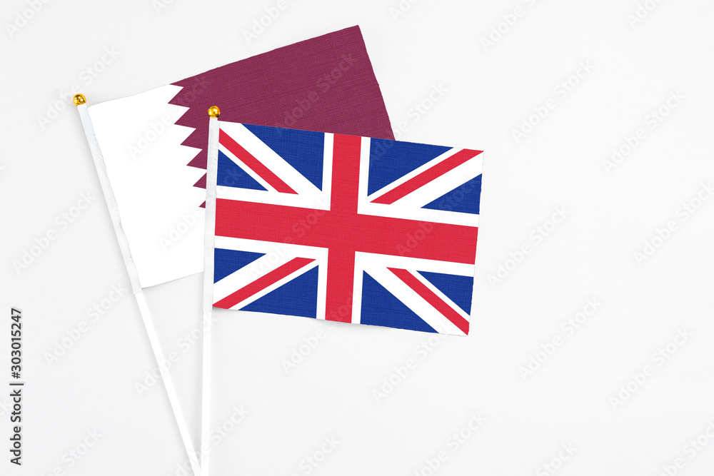 United Kingdom and Qatar stick flags on white background. High quality fabric, miniature national flag. Peaceful global concept.White floor for copy space. United Kingdom and Qatar stick flags on white background. High quality fabric, miniature national flag. Peaceful global concept.White floor for copy space.