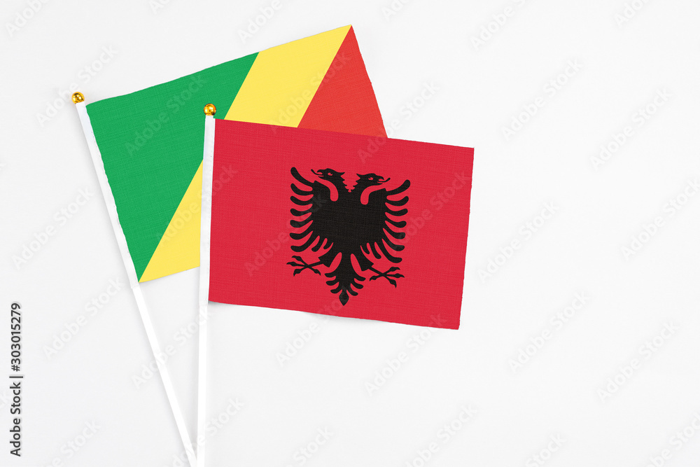 Obraz premium Albania and Republic Of The Congo stick flags on white background. High quality fabric, miniature national flag. Peaceful global concept.White floor for copy space.