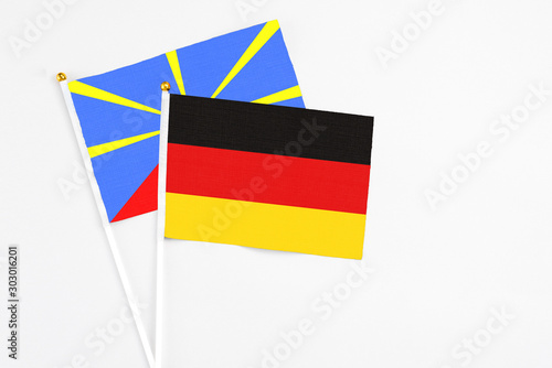 Germany and Reunion stick flags on white background. High quality fabric  miniature national flag. Peaceful global concept.White floor for copy space.