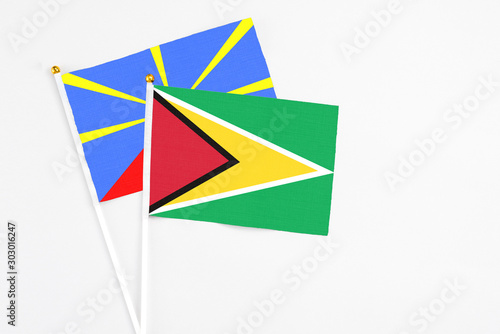Free Download Guyana and Reunion stick flags on white background. High quality fabric, miniature national flag. Peaceful global concept.White floor for copy space. - GFXLoad