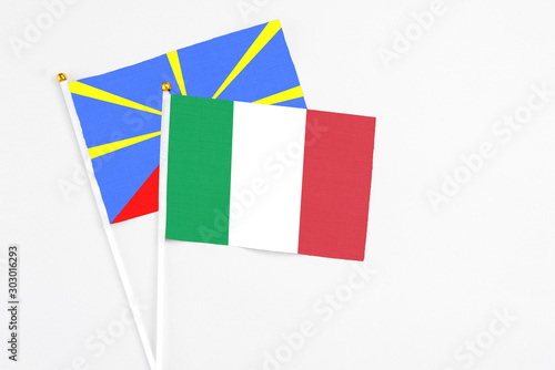 Italy and Reunion stick flags on white background. High quality fabric, miniature national flag. Peaceful global concept.White floor for copy space.