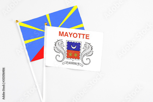 Mayotte and Reunion stick flags on white background. High quality fabric, miniature national flag. Peaceful global concept.White floor for copy space.