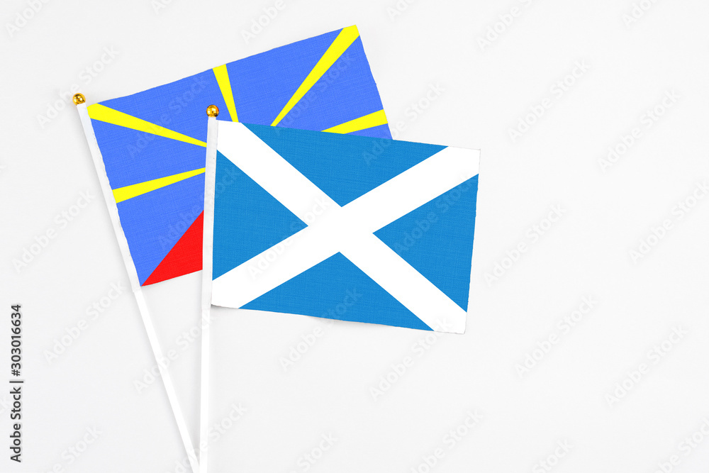 Scotland and Reunion stick flags on white background. High quality fabric, miniature national flag. Peaceful global concept.White floor for copy space. Scotland and Reunion stick flags on white background. High quality fabric, miniature national flag. Peaceful global concept.White floor for copy space.