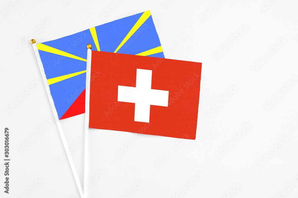 Switzerland and Reunion stick flags on white background. High quality fabric, miniature national flag. Peaceful global concept.White floor for copy space.