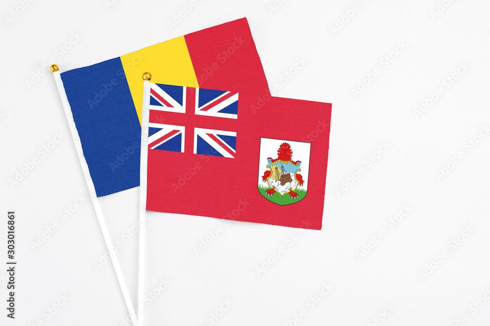Fototapeta premium Bermuda and Romania stick flags on white background. High quality fabric, miniature national flag. Peaceful global concept.White floor for copy space.