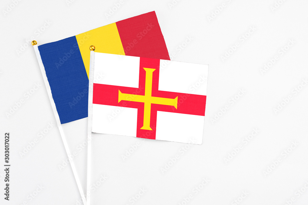 Guernsey and Romania stick flags on white background. High quality fabric, miniature national flag. Peaceful global concept.White floor for copy space.