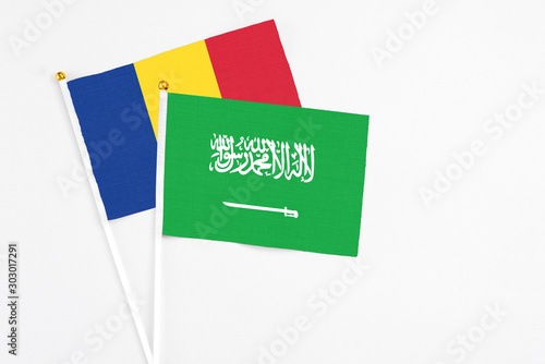 Saudi Arabia and Romania stick flags on white background. High quality fabric, miniature national flag. Peaceful global concept.White floor for copy space.