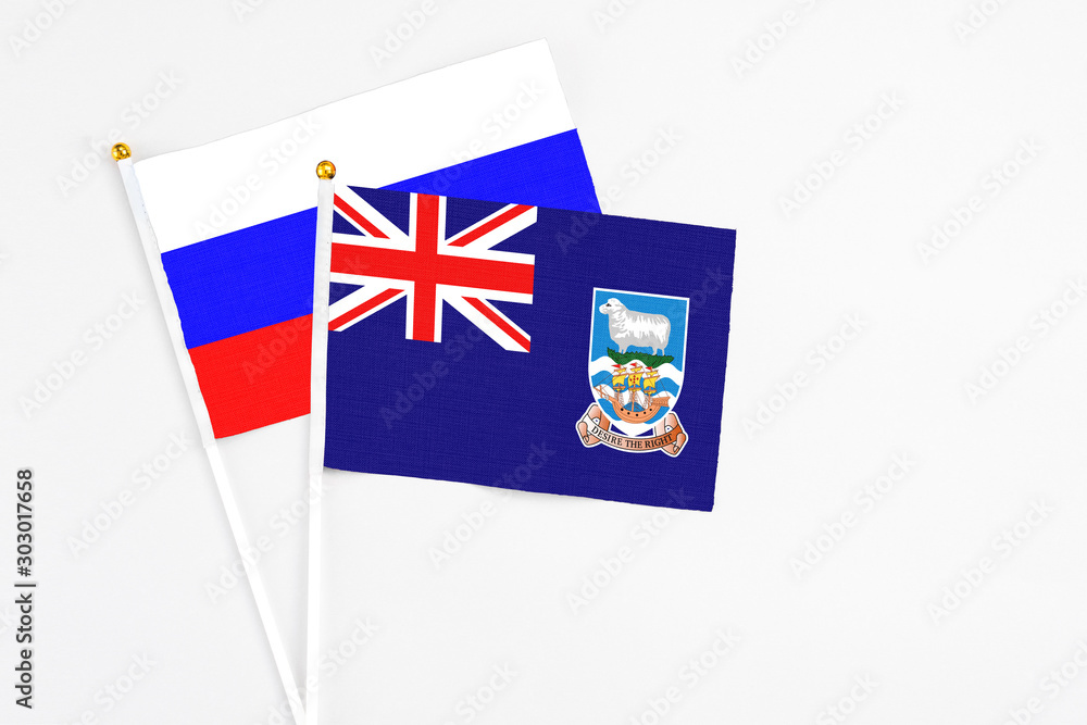 Fototapeta premium Falkland Islands and Russia stick flags on white background. High quality fabric, miniature national flag. Peaceful global concept.White floor for copy space.