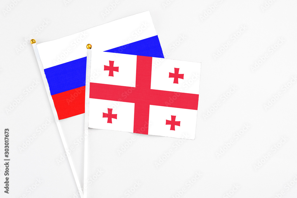 Georgia and Russia stick flags on white background. High quality fabric, miniature national flag. Peaceful global concept.White floor for copy space.