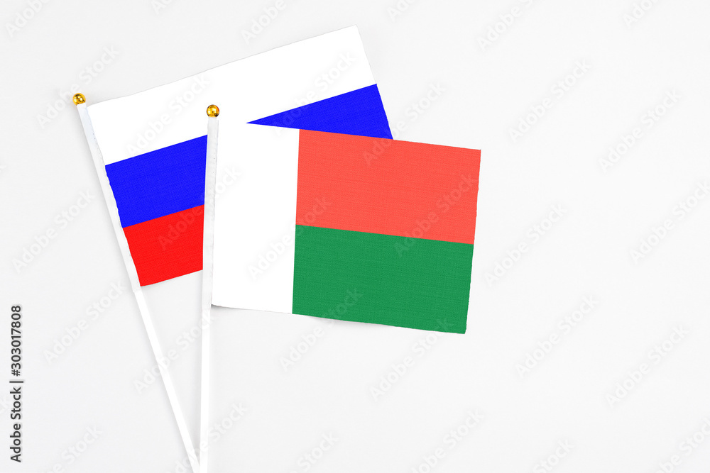 Madagascar and Russia stick flags on white background. High quality fabric, miniature national flag. Peaceful global concept.White floor for copy space. Madagascar and Russia stick flags on white background. High quality fabric, miniature national flag. Peaceful global concept.White floor for copy space.