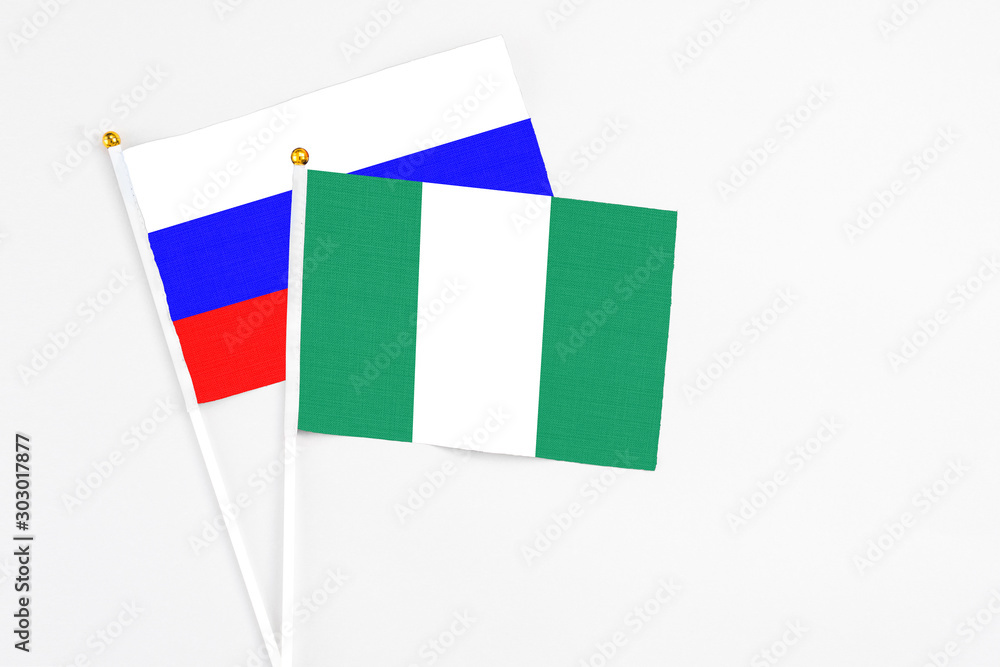 Nigeria and Russia stick flags on white background. High quality fabric, miniature national flag. Peaceful global concept.White floor for copy space. Nigeria and Russia stick flags on white background. High quality fabric, miniature national flag. Peaceful global concept.White floor for copy space.
