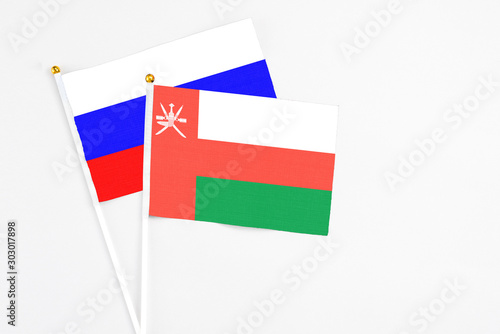Free Download Oman and Russia stick flags on white background. High quality fabric, miniature national flag. Peaceful global concept.White floor for copy space. - GFXLoad