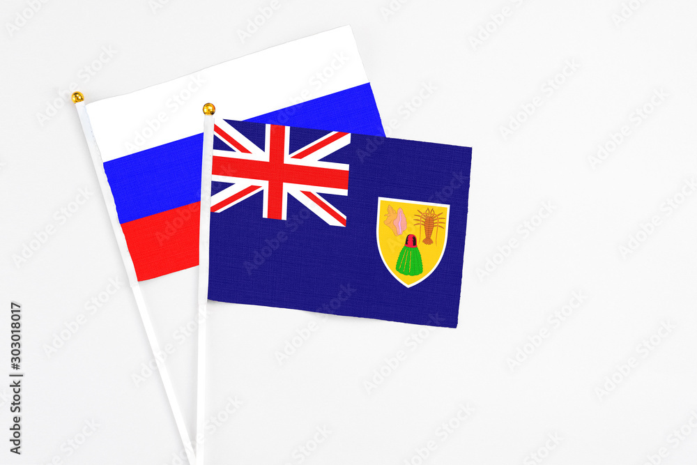Fototapeta premium Turks And Caicos Islands and Russia stick flags on white background. High quality fabric, miniature national flag. Peaceful global concept.White floor for copy space.