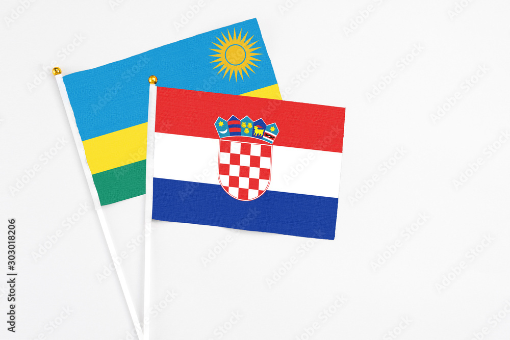 Naklejka premium Croatia and Rwanda stick flags on white background. High quality fabric, miniature national flag. Peaceful global concept.White floor for copy space.
