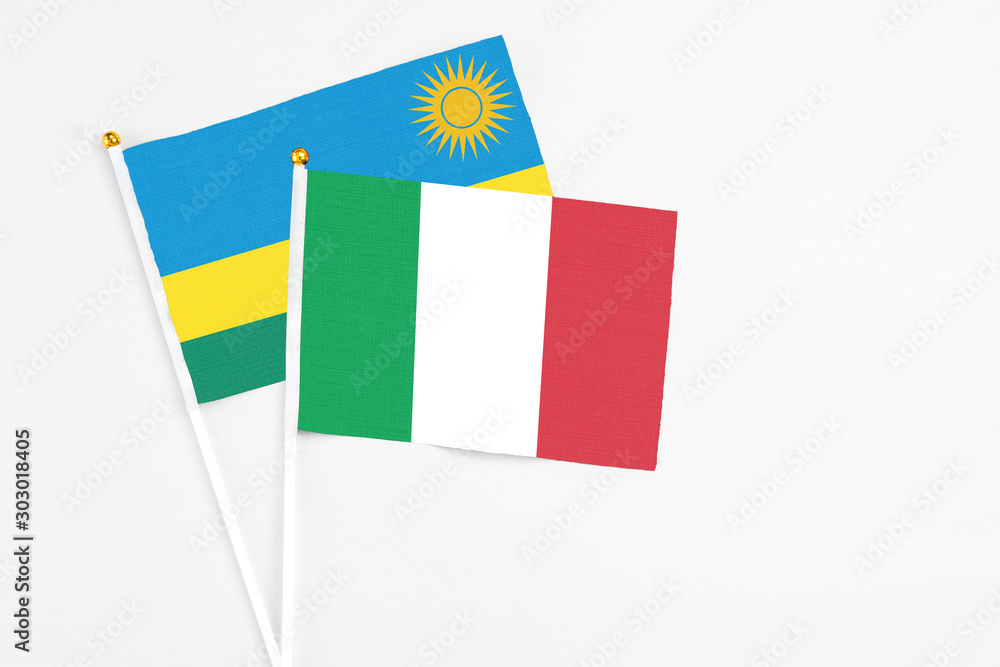 Fototapeta premium Italy and Rwanda stick flags on white background. High quality fabric, miniature national flag. Peaceful global concept.White floor for copy space.