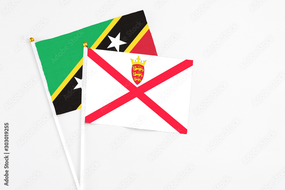 Jersey and Saint Kitts And Nevis stick flags on white background. High quality fabric, miniature national flag. Peaceful global concept.White floor for copy space. Jersey and Saint Kitts And Nevis stick flags on white background. High quality fabric, miniature national flag. Peaceful global concept.White floor for copy space.