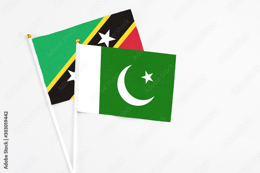 Pakistan and Saint Kitts And Nevis stick flags on white background. High quality fabric, miniature national flag. Peaceful global concept.White floor for copy space. Pakistan and Saint Kitts And Nevis stick flags on white background. High quality fabric, miniature national flag. Peaceful global concept.White floor for copy space.