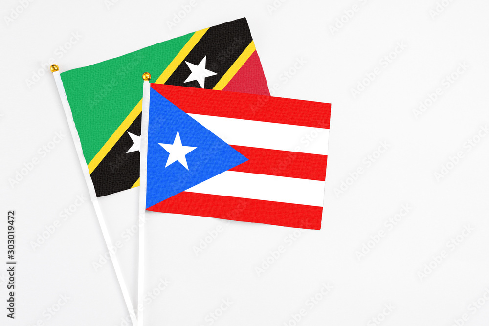 Puerto Rico and Saint Kitts And Nevis stick flags on white background. High quality fabric, miniature national flag. Peaceful global concept.White floor for copy space. Puerto Rico and Saint Kitts And Nevis stick flags on white background. High quality fabric, miniature national flag. Peaceful global concept.White floor for copy space.