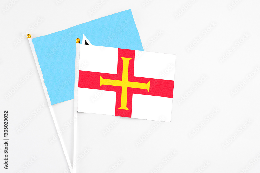 Guernsey and Saint Lucia stick flags on white background. High quality fabric, miniature national flag. Peaceful global concept.White floor for copy space.
