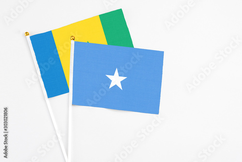 Free Download Somalia and Saint Vincent And The Grenadines stick flags on white background. High quality fabric, miniature national flag. Peaceful global concept.White floor for copy space. - GFXLoad