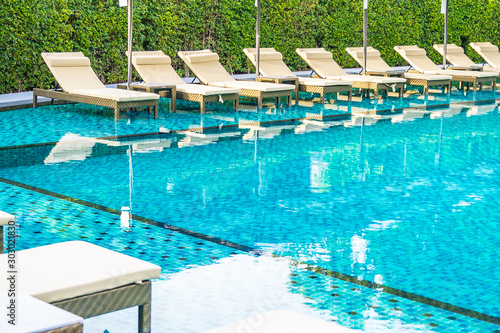 Umbrella and chair sofa around outdoor swimming pool in hotel resort for holiday vacation