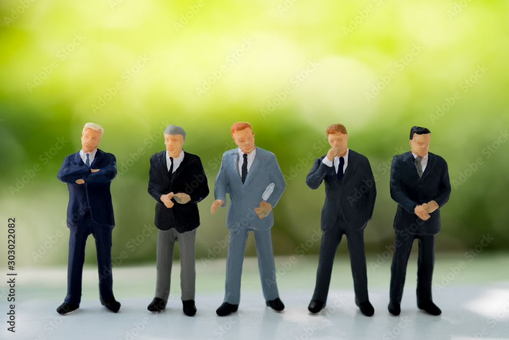 Miniature people : business man standing together and think how to earn more money, stand in front of green nature background Miniature people : business man standing together and think how to earn more money, stand in front of green nature background