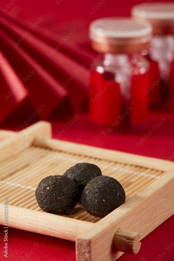 Chinese style red background with red folding fan and red pill bottle, three Chinese medicine pills placed on bamboo basket Chinese style red background with red folding fan and red pill bottle, three Chinese medicine pills placed on bamboo basket
