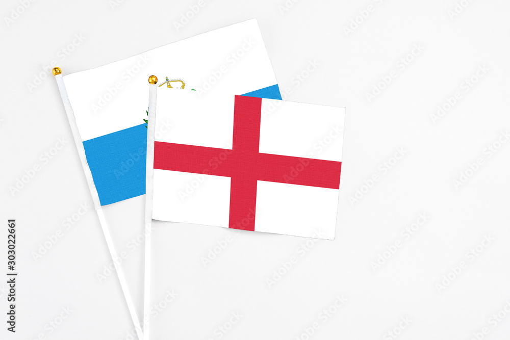 England and San Marino stick flags on white background. High quality fabric, miniature national flag. Peaceful global concept.White floor for copy space.