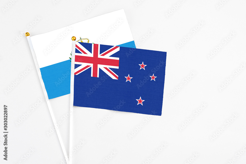 Fototapeta premium New Zealand and San Marino stick flags on white background. High quality fabric, miniature national flag. Peaceful global concept.White floor for copy space.