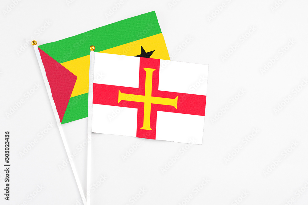 Guernsey and Sao Tome And Principe stick flags on white background. High quality fabric, miniature national flag. Peaceful global concept.White floor for copy space.