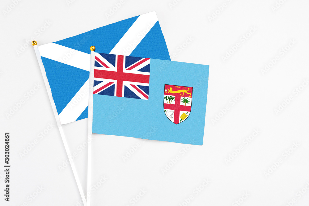 Fiji and Scotland stick flags on white background. High quality fabric, miniature national flag. Peaceful global concept.White floor for copy space.