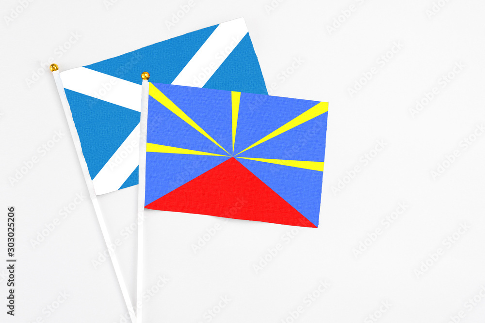Reunion and Scotland stick flags on white background. High quality fabric, miniature national flag. Peaceful global concept.White floor for copy space.