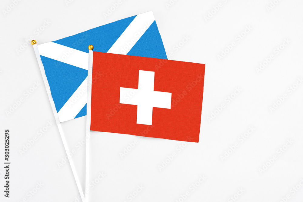 Switzerland and Scotland stick flags on white background. High quality fabric, miniature national flag. Peaceful global concept.White floor for copy space.