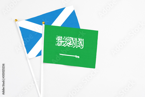 Saudi Arabia and Scotland stick flags on white background. High quality fabric, miniature national flag. Peaceful global concept.White floor for copy space.