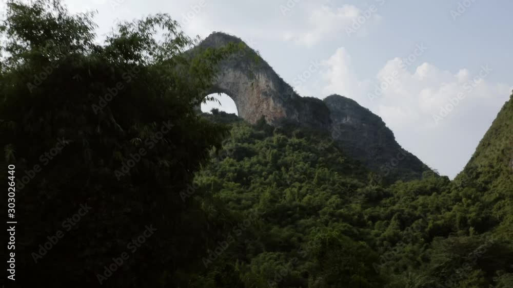 Moon Hill karst mountain natural arch, China, aerial reveal through valley trees Moon Hill karst mountain natural arch, China, aerial reveal through valley trees