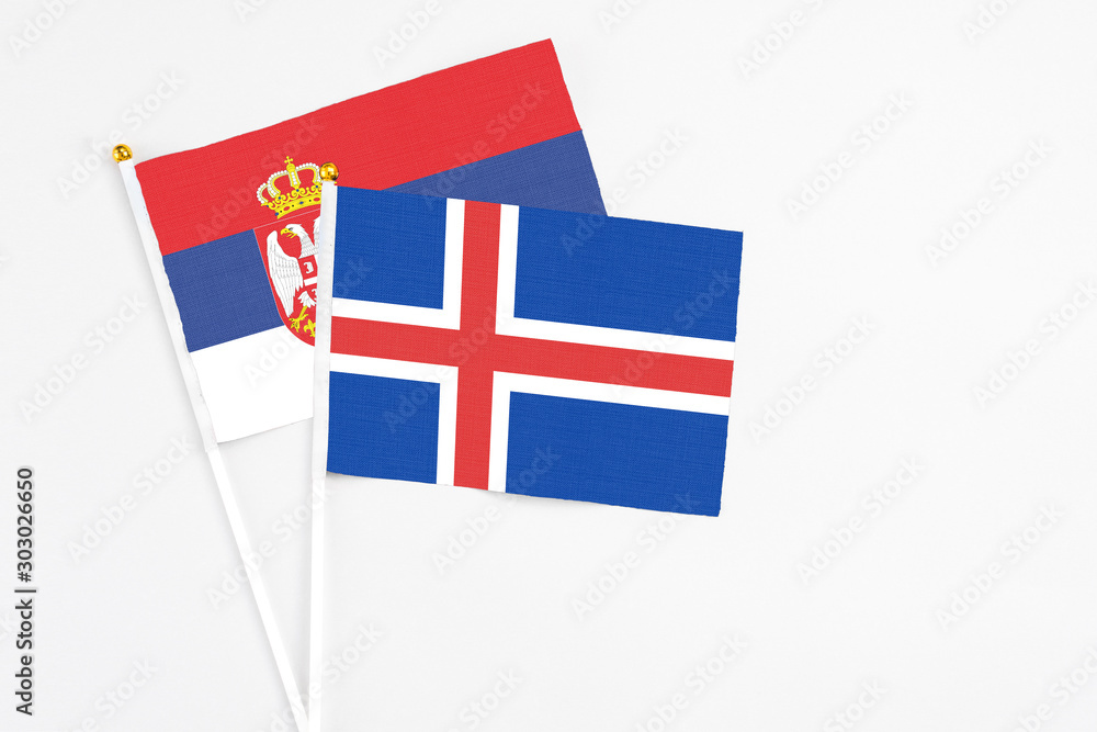 Iceland and Serbia stick flags on white background. High quality fabric, miniature national flag. Peaceful global concept.White floor for copy space.