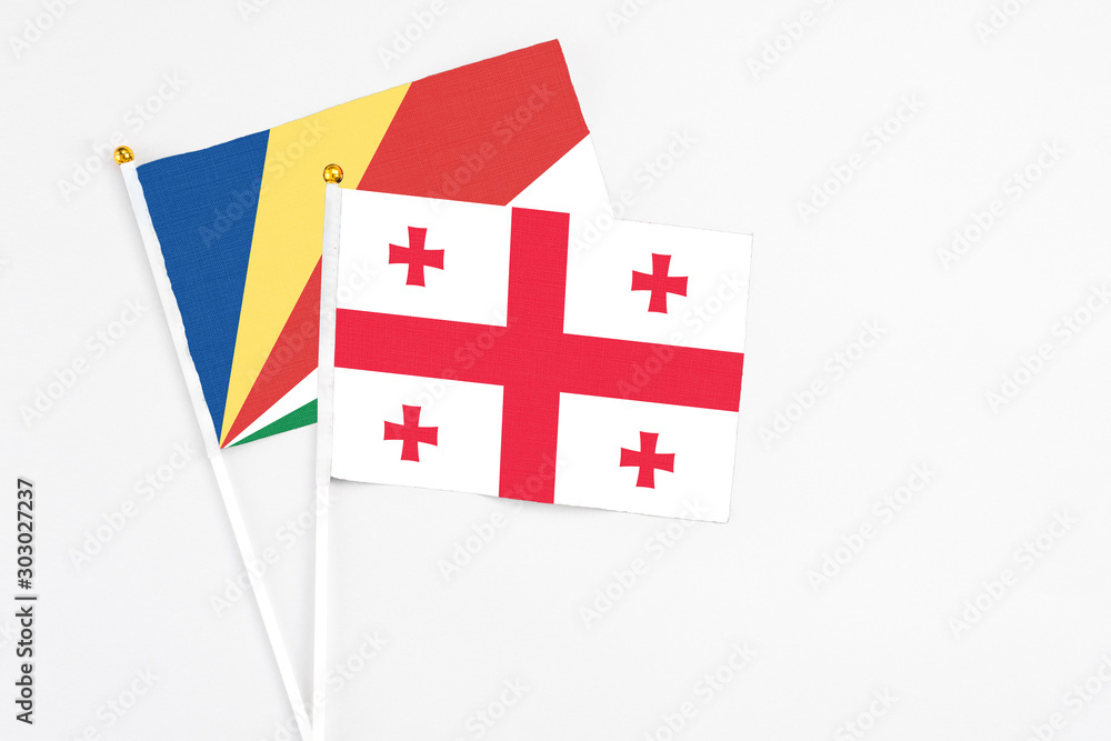 Georgia and Seychelles stick flags on white background. High quality fabric, miniature national flag. Peaceful global concept.White floor for copy space.v
