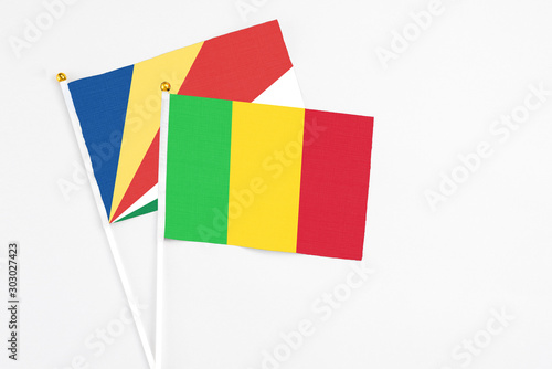 Mali and Seychelles stick flags on white background. High quality fabric, miniature national flag. Peaceful global concept.White floor for copy space.v